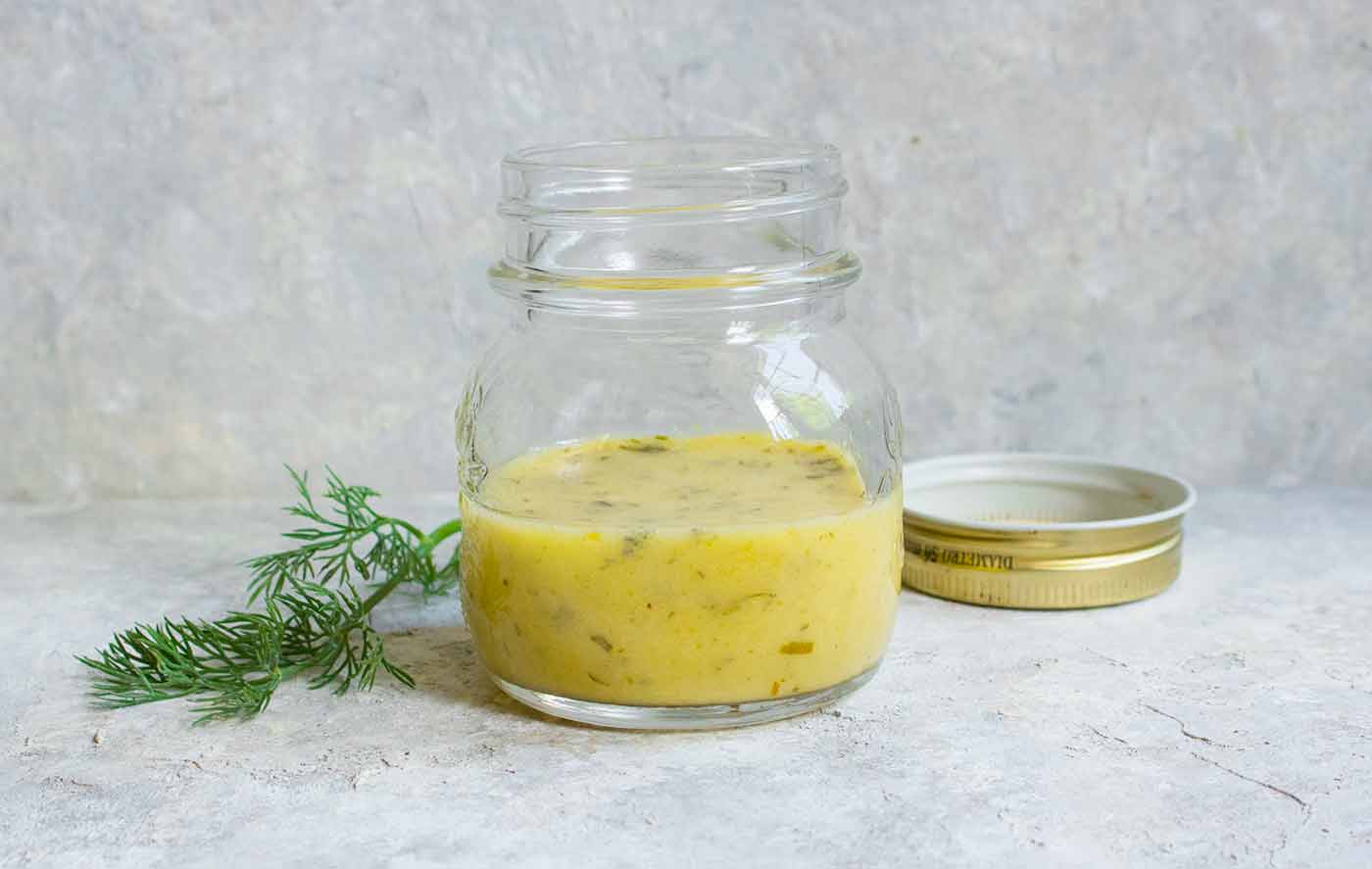 A jar of homemade lemon dill dressing for the Summer Cauliflower Power Salad