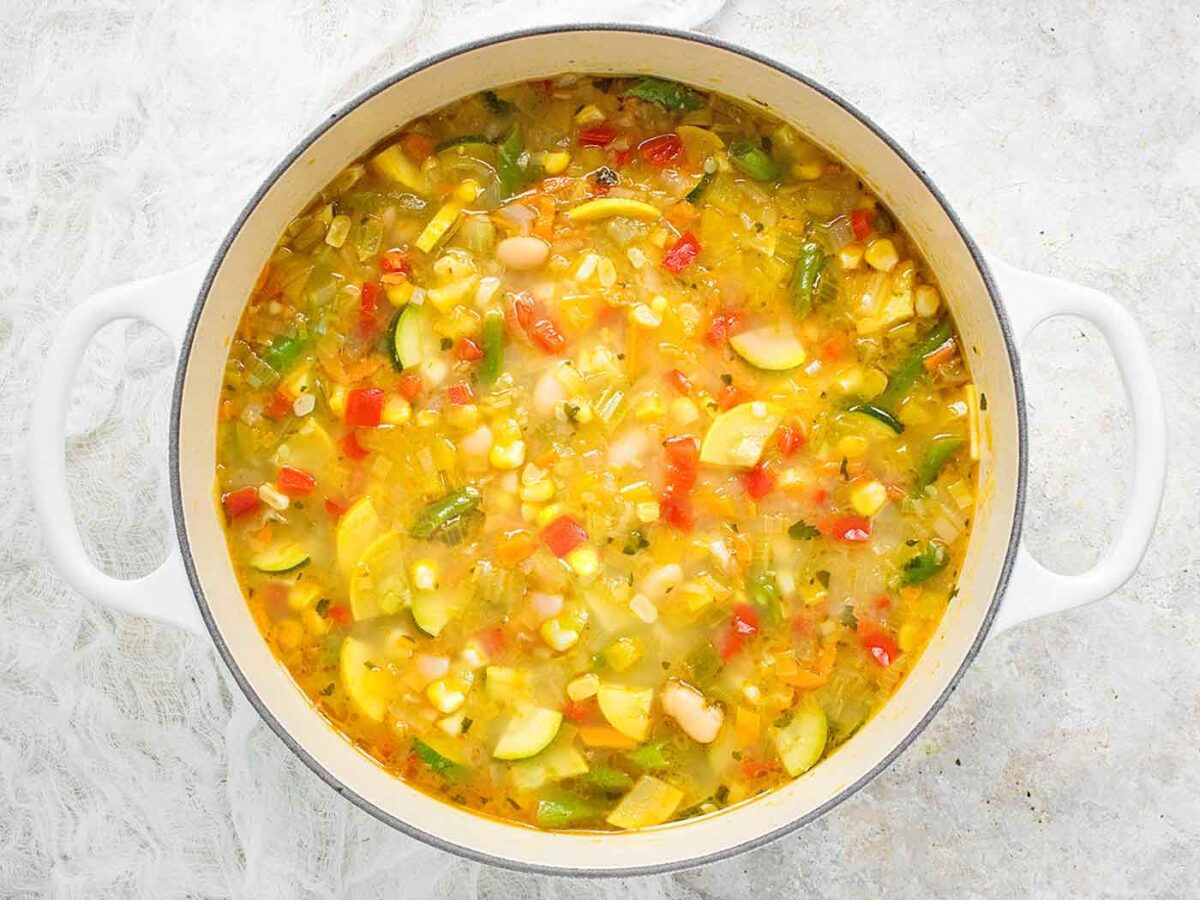 Overhead view of Summer Minestrone soup in a white Dutch oven.