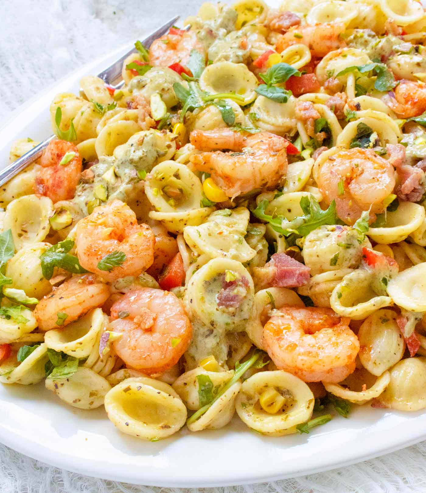 Angled side view of pasta salad on a white serving platter.