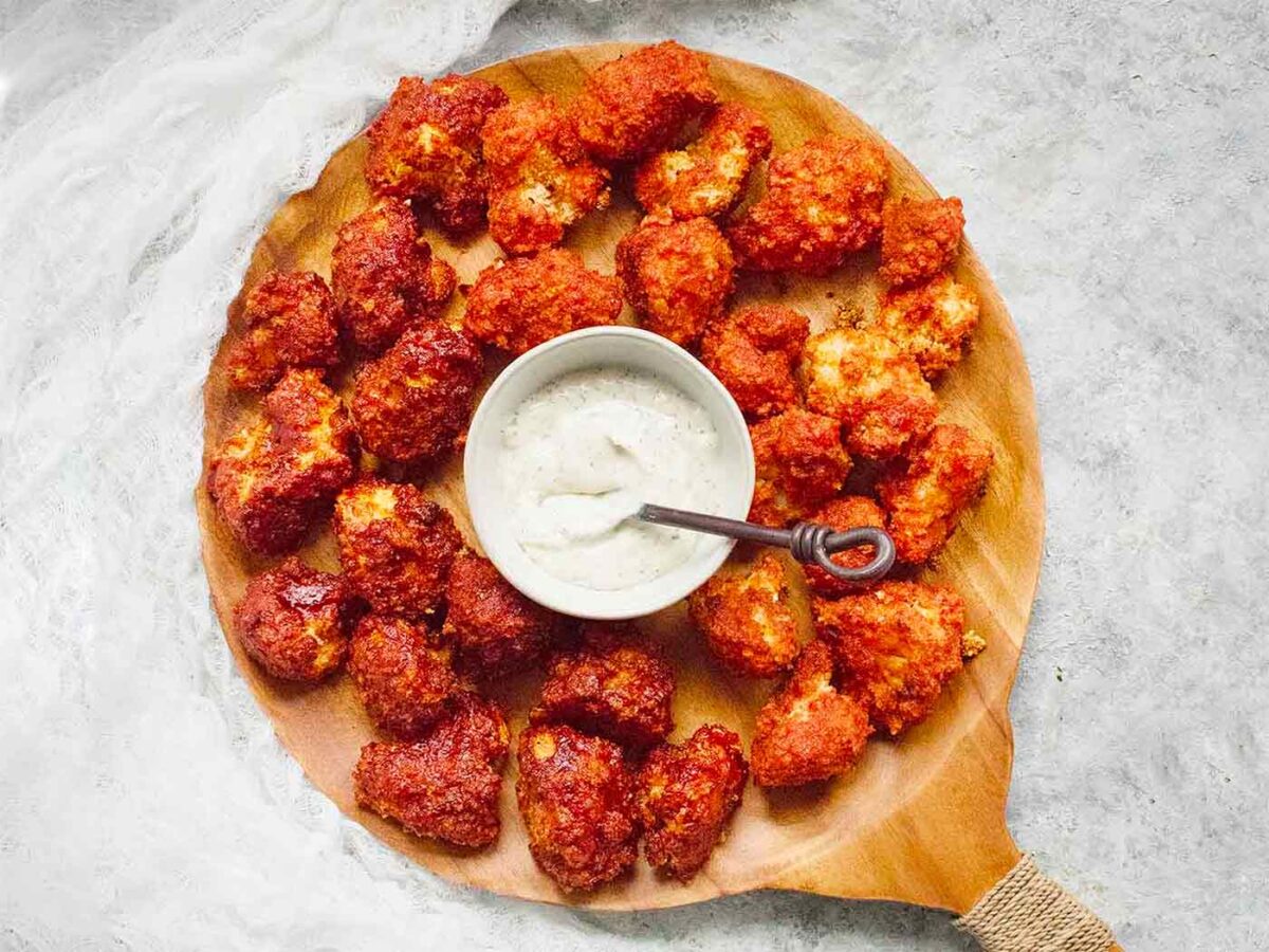 Sweet & Spicy Cauliflower Bites on a wooden serving tray with ranch dip.