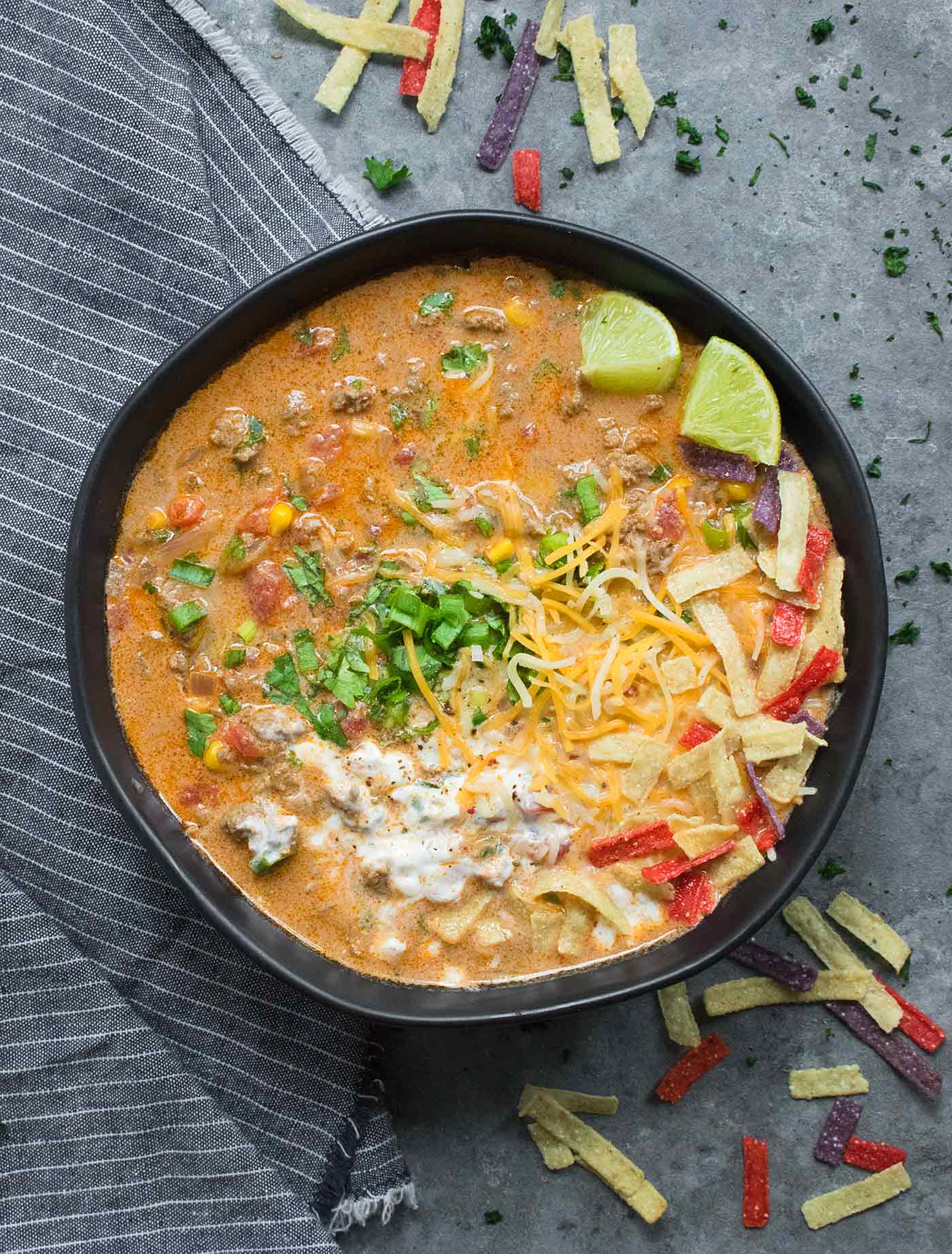 Taco Soup in a large black soup bowl, with toppings.