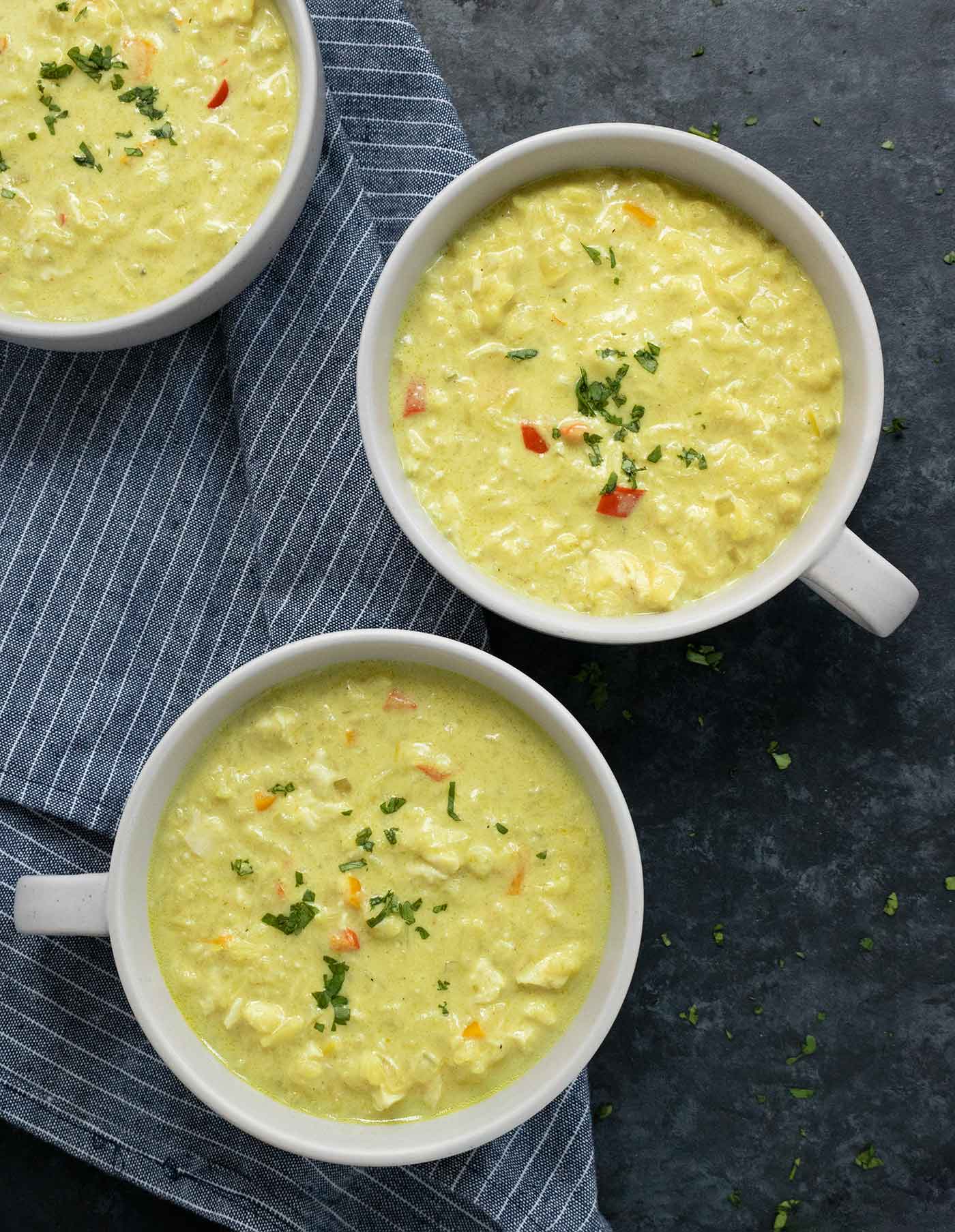 Three bowls of Thai Coconut Chicken Soup on a black background.