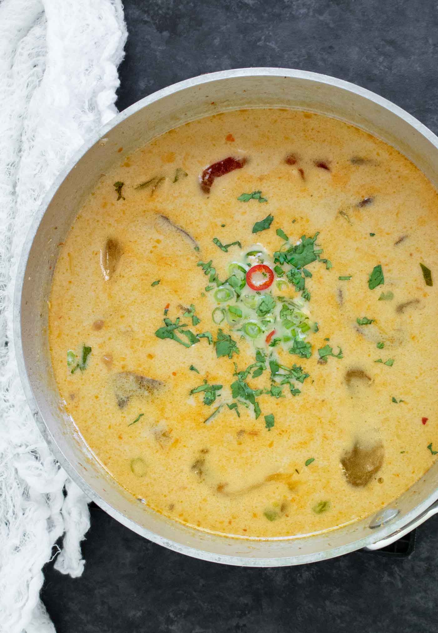 An overhead view of Thai Coconut Mushroom Soup in a stainless steel pot.