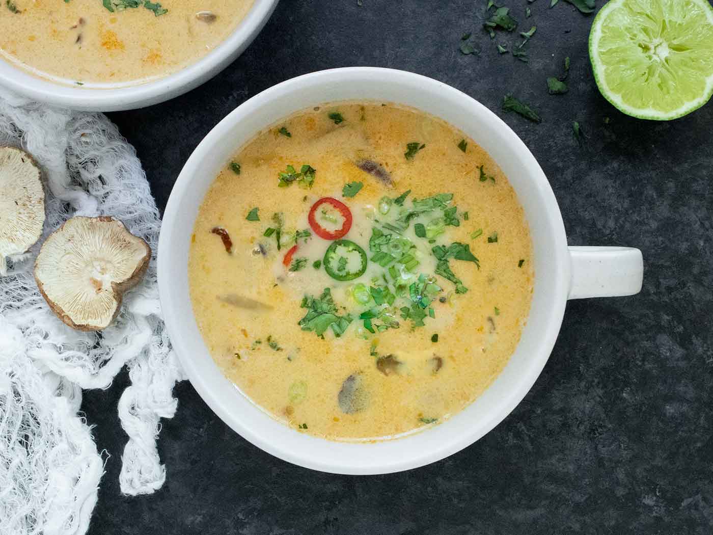 An overhead shot of Thai Coconut Mushroom Soup in a handled white bowl.