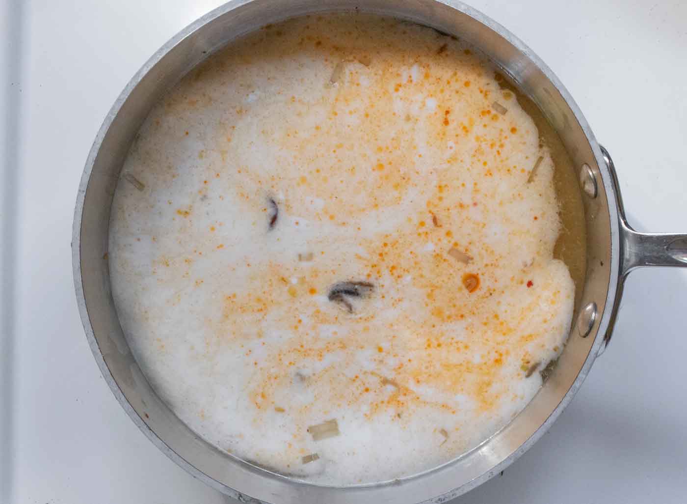 Adding the broth and coconut milk to the pot.