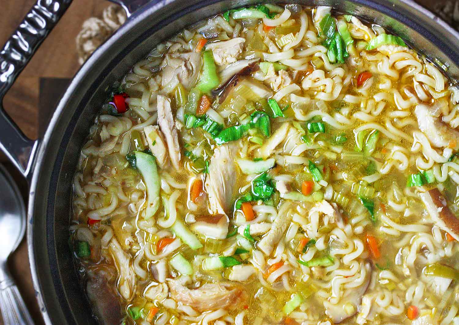 Overhead and close-up view of a pot of Thai Ramen Noodle Chicken Soup.