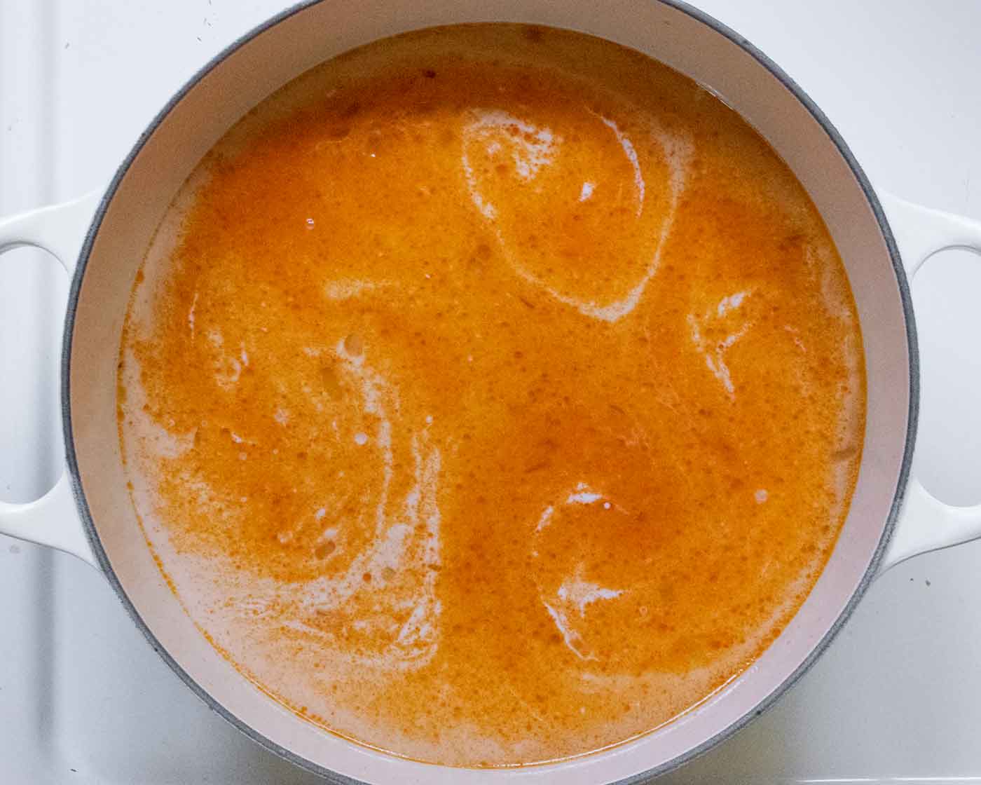 Adding the soup liquids to the pot.