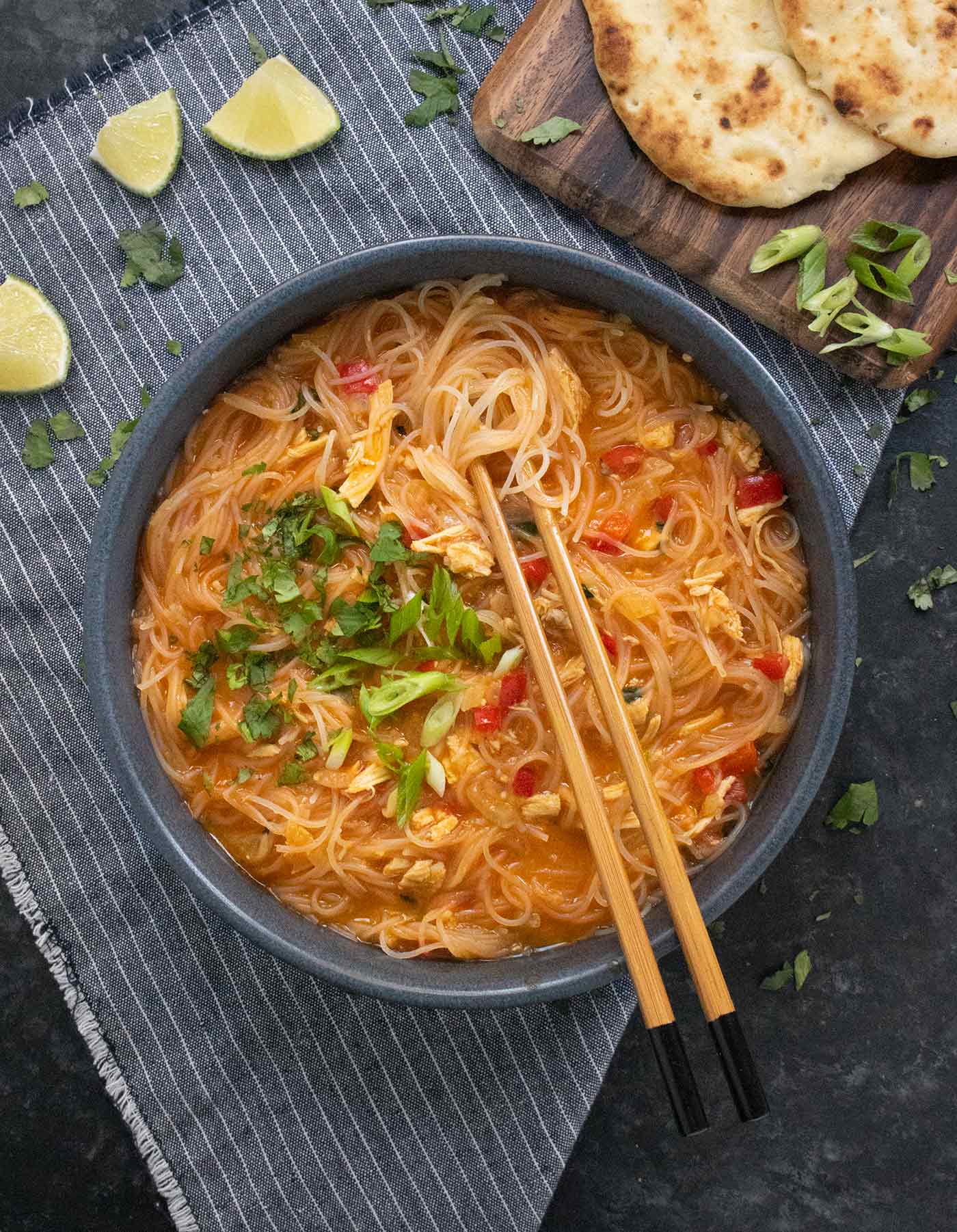 Thai Red Curry Noodle Soup in a stone blue bowl with chopsticks.