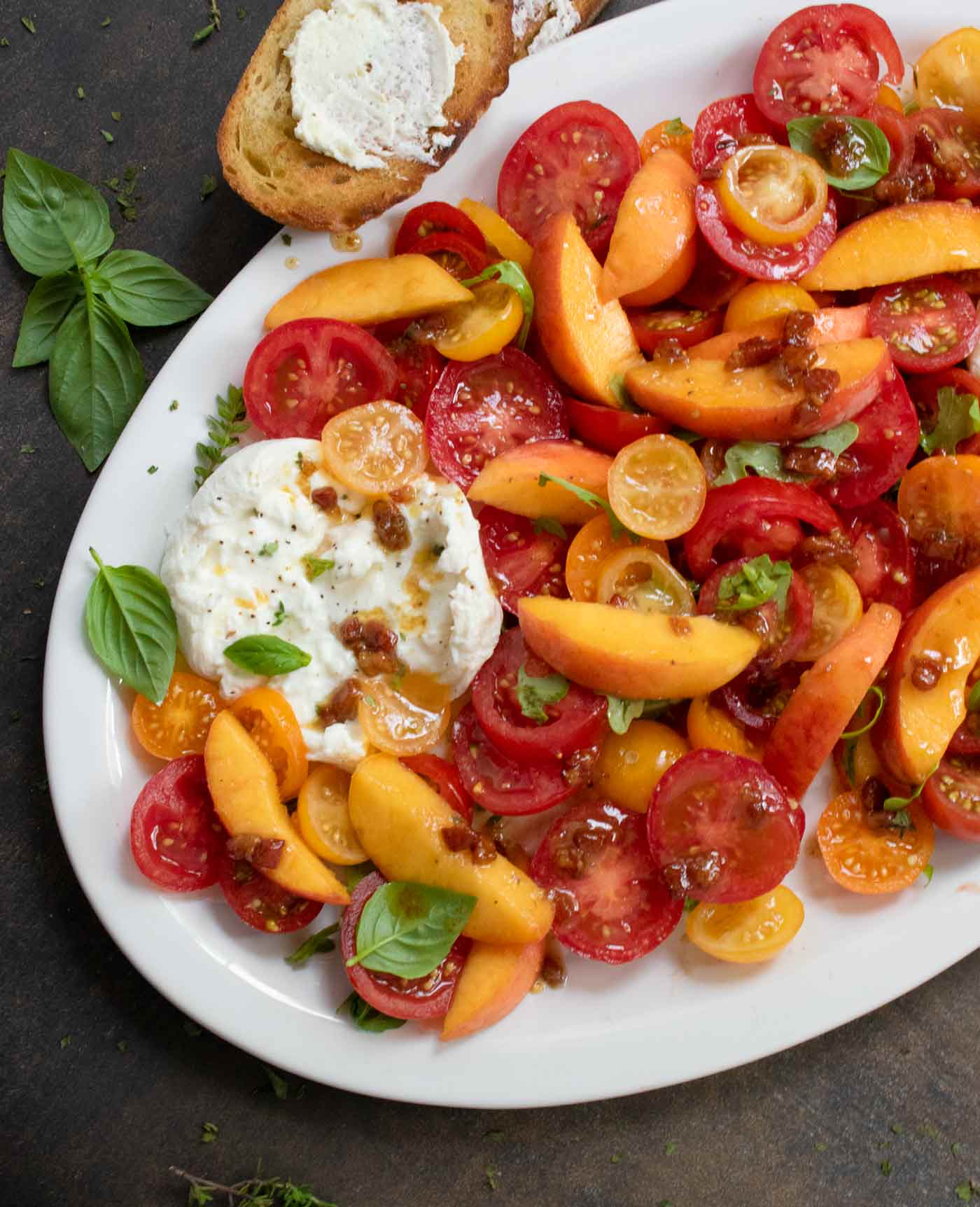 Tomato Peach Burrata Salad on a white platter.