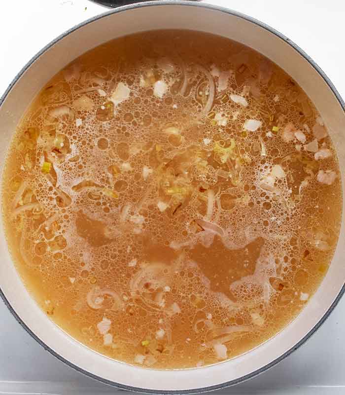Chicken broth coming up to a boil in the soup.