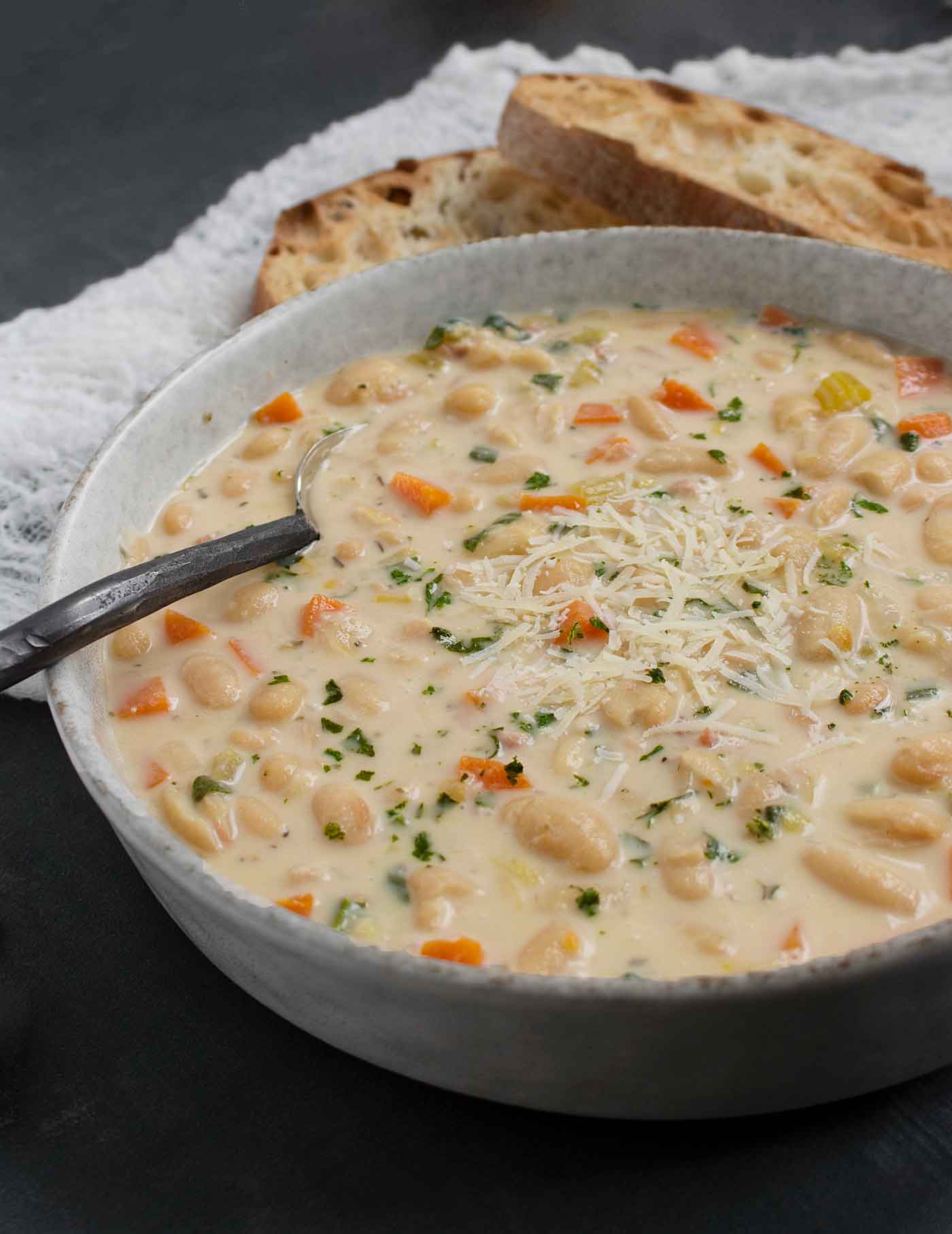 Side angled view of a bowl of Tuscan White Bean Soup with a spoon.