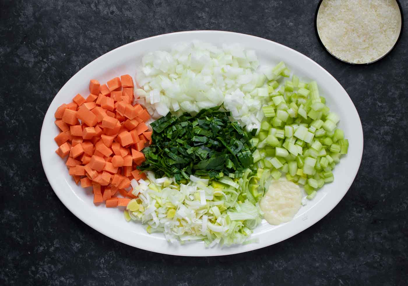Aromatics prepped and ready to use, displayed on an oval white serving plate.
