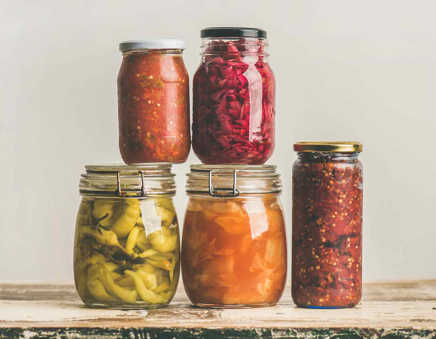 Jars of various colorful fermented products, stacked on top of each other.