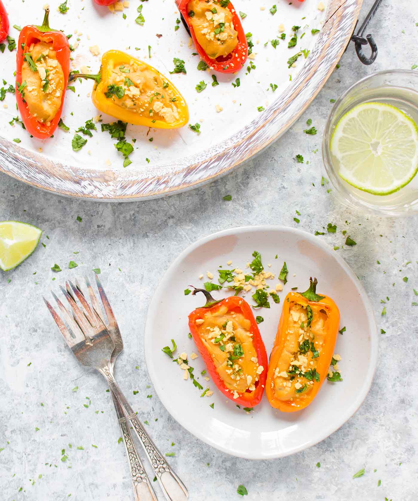 Two vegan queso stuffed mini peppers on an appetizer plate
