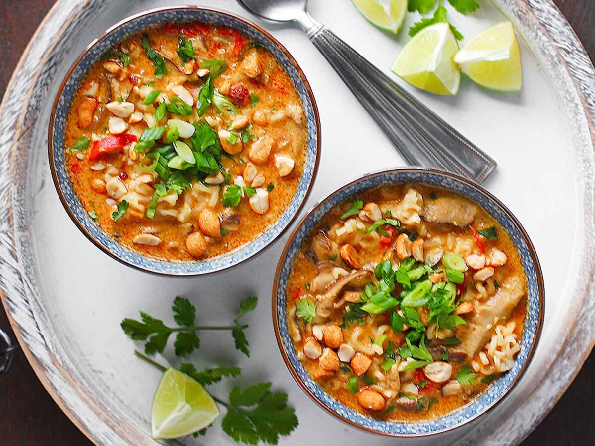 Overhead view of two bowls of Vegetarian Thai Peanut Soup on a white serving tray.