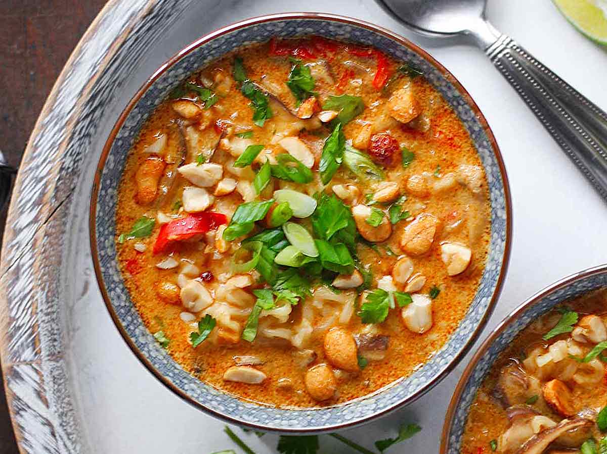 Vegetarian Thai Peanut Soup in a bowl on a white wooden serving tray.
