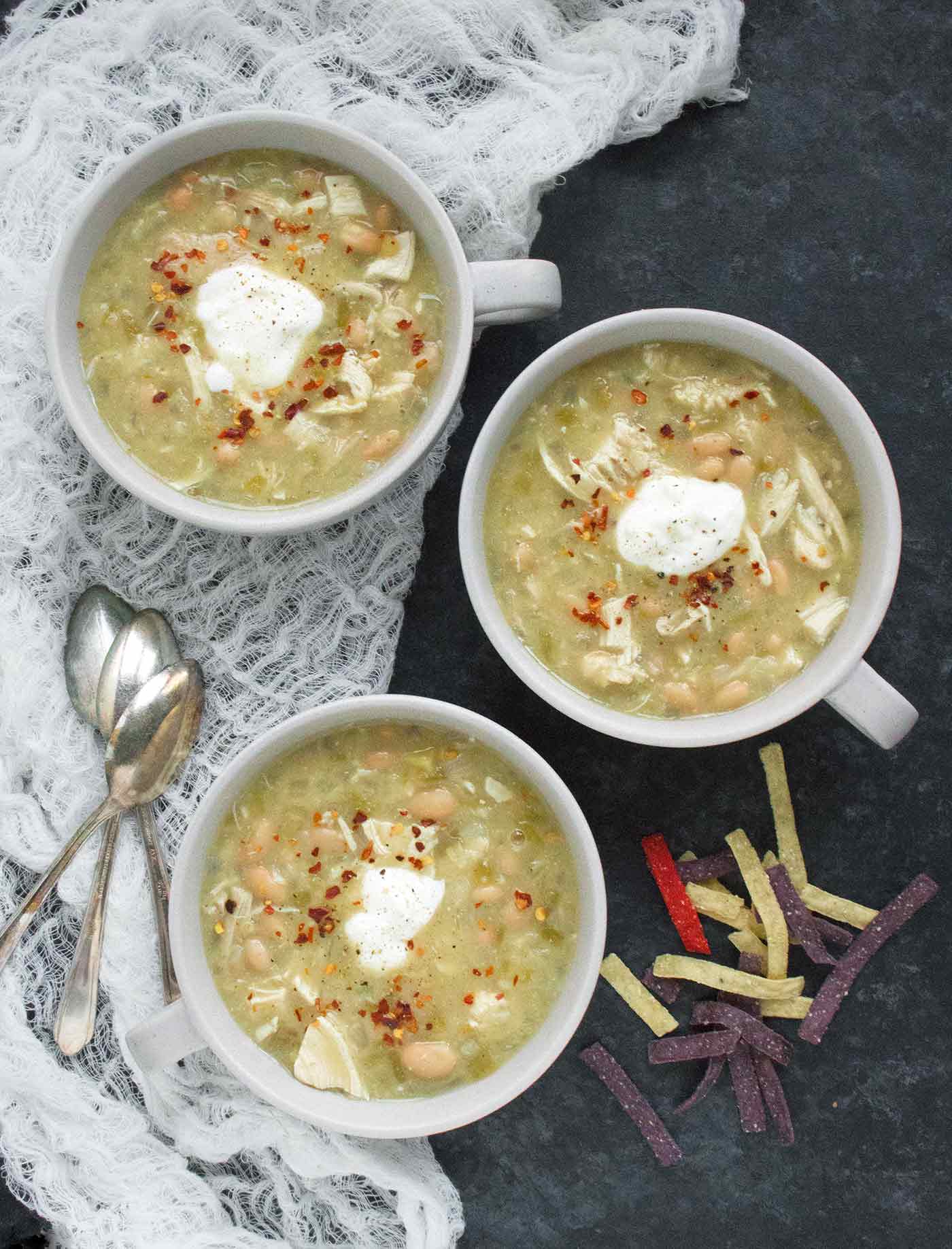 Three bowls of chicken chili on a dark background