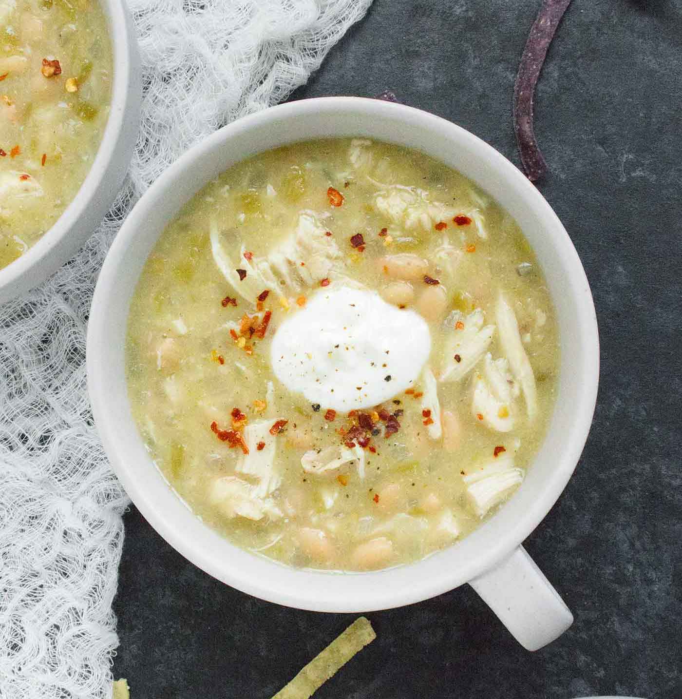 A bowl of white chicken chili with a dollop of sour cream