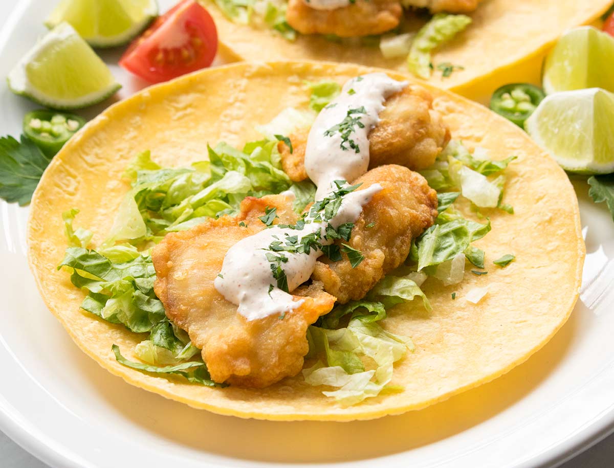 A fish taco topped with fish taco sauce