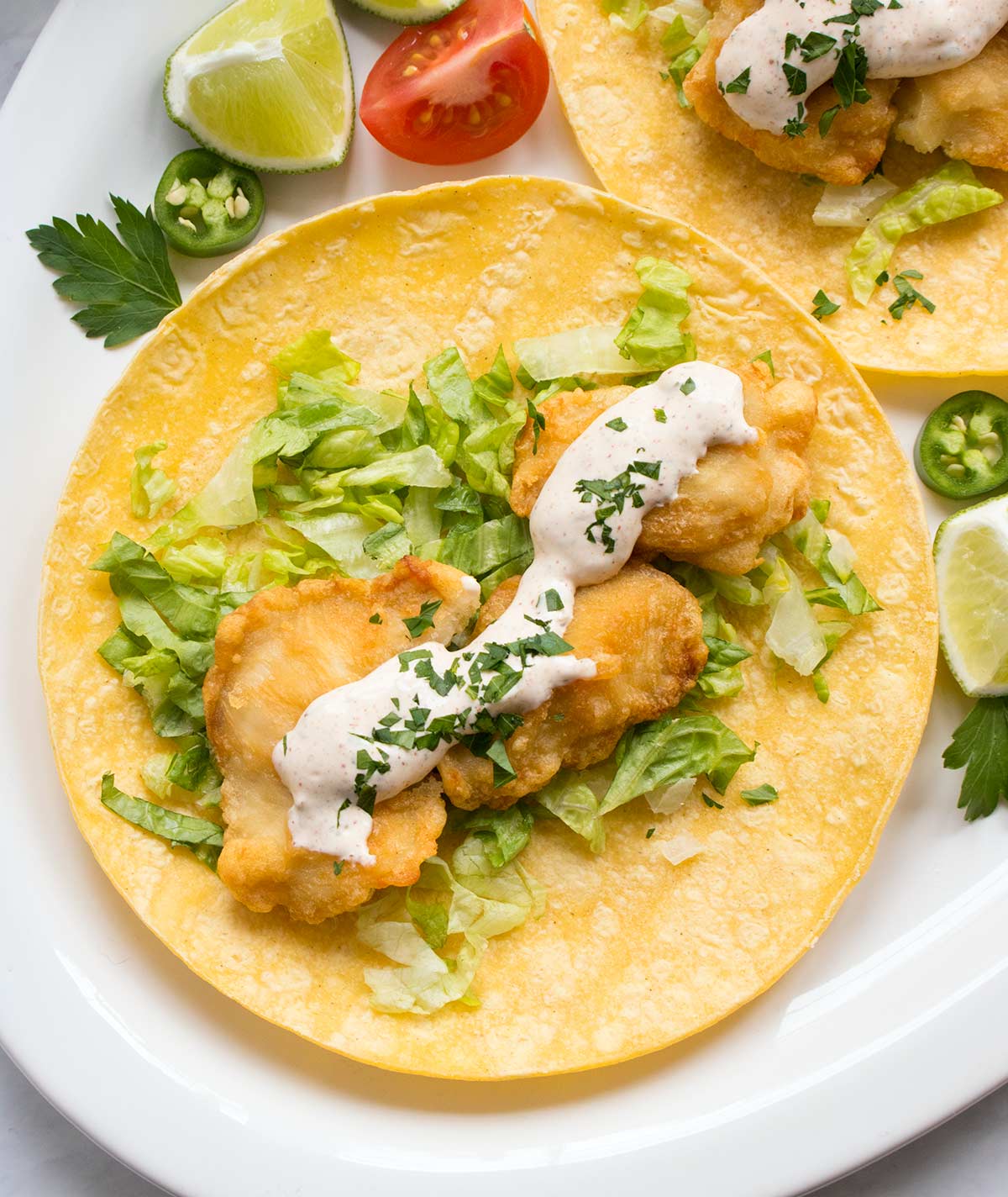 Homemade sauce on fish tacos and corn tortillas.