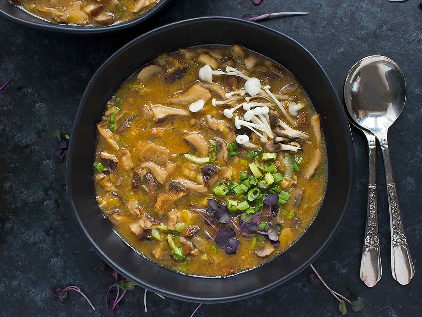 Wild Mushroom Miso Soup in a black bowl, topped with garnishes.