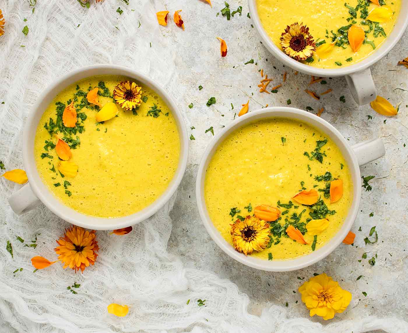 Three bowls of yellow gazpacho